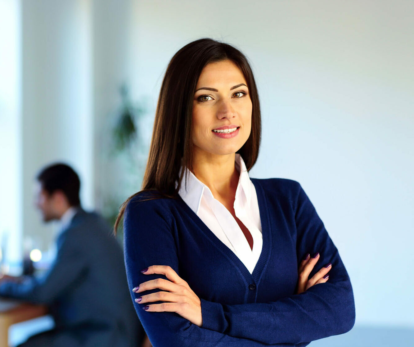 Smiling businesswoman standing with arms folded in front of colleagues